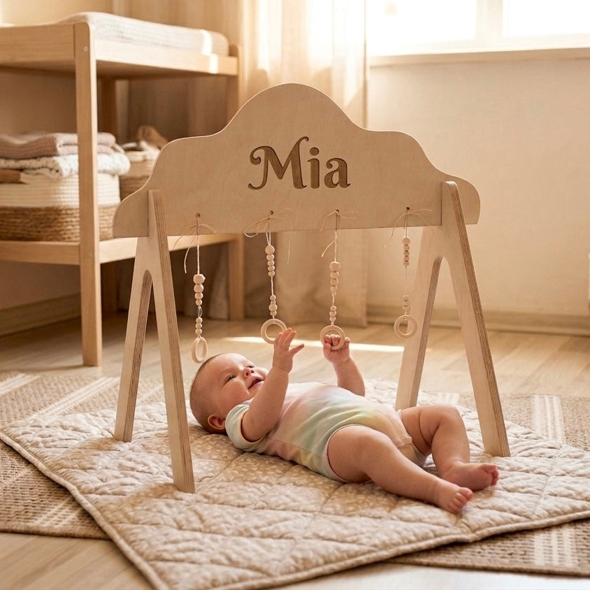 Baby lying on a rug next to a wooden baby gym with 'Mia' on it, in a home setting.