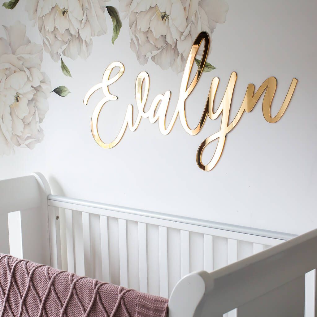 Nursery with a white crib and floral wall art, featuring the name 'Evalyn' in gold.