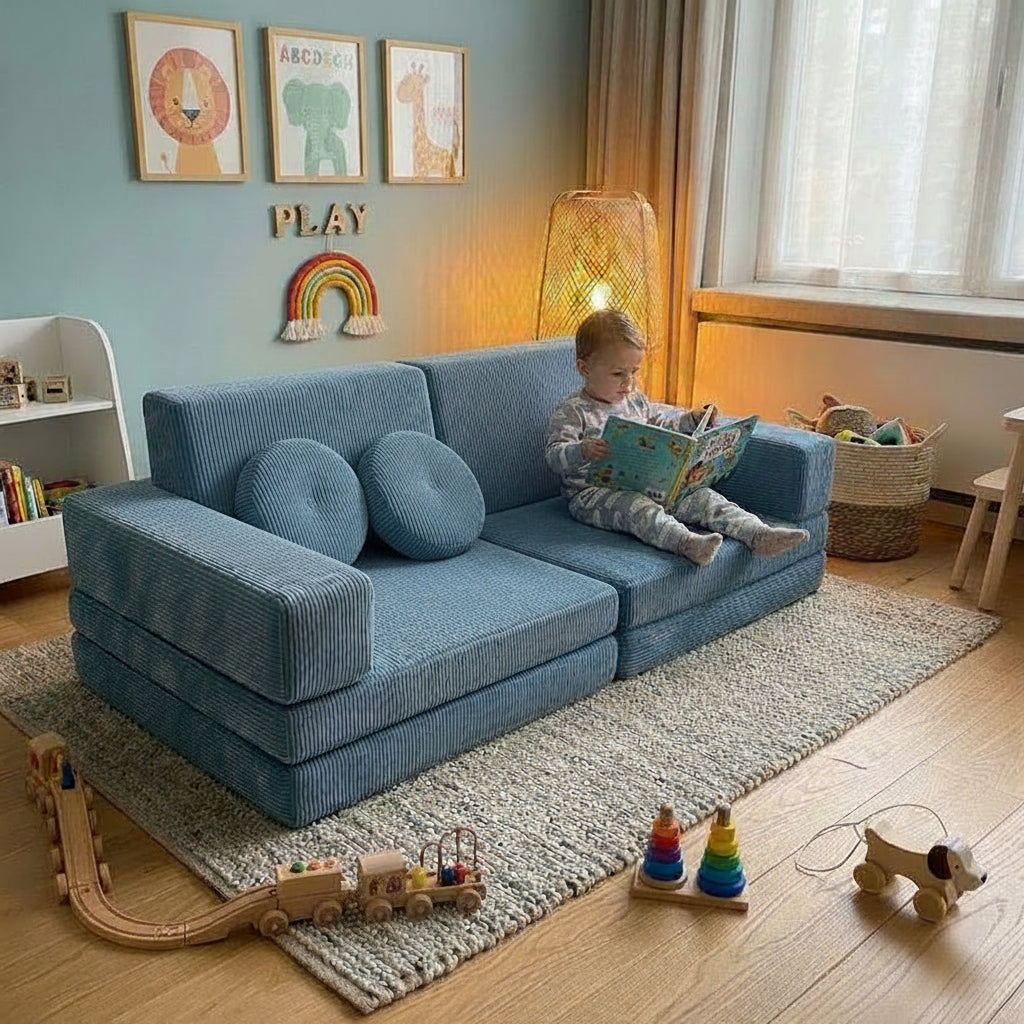 Child reading a book on a blue play couch in a cozy toddlers room.