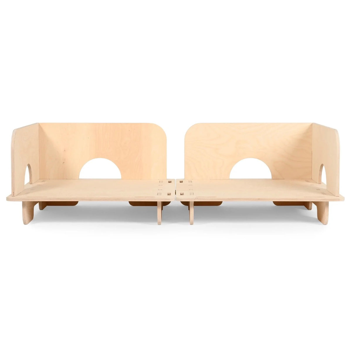 A light natural wood modular play couch or bench made of plywood, featuring two raised backrests with circular cutouts and short legs, shown on a plain white background.