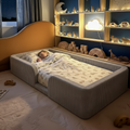 Child sleeping in a floor bed with a shelf of toys and decorative items in the background