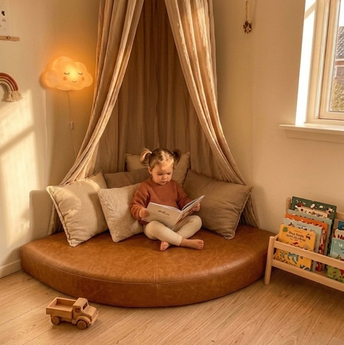 Child reading a book in a cozy reading nook with a canopy and pillows.