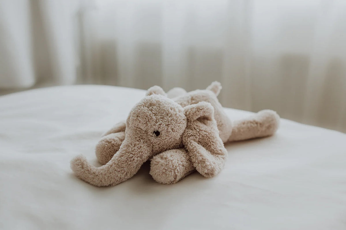 Plush elephant toy on a white surface with a blurred background